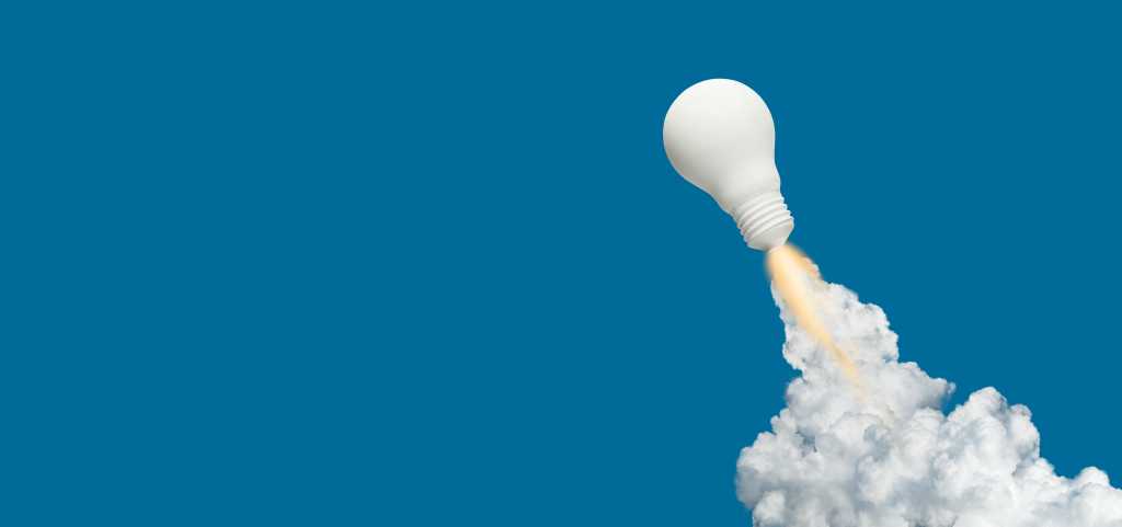 white light bulb blasts off like a rocket trailing fire and smoke against a blue background